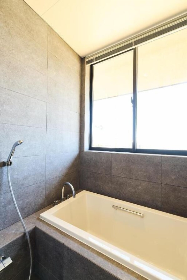 A bathroom with a bathtub, a window, and a shower. - DEAR MOM (Onjuku)