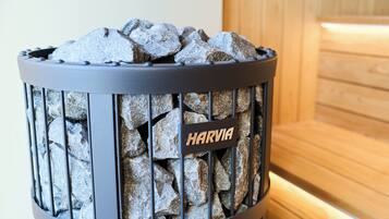 Un recipiente de metal negro lleno de piedras con la etiqueta 'HARVIA'.