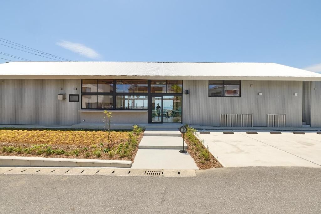 A modern building with a flat roof, large windows, and a small entrance area with a sign.