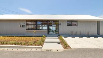 A modern building with a flat roof, large windows, and a small entrance area with a sign.