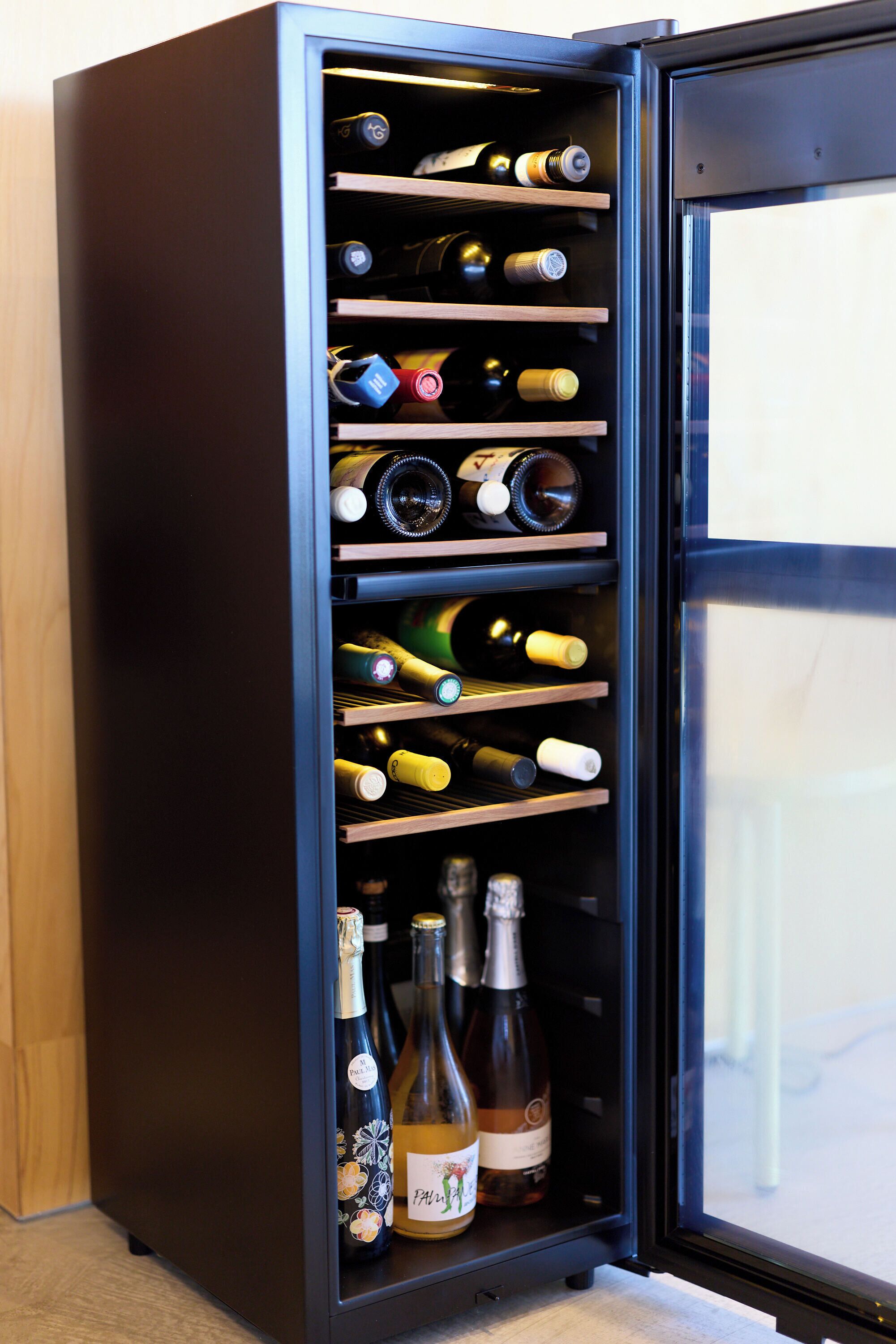 A wine refrigerator with multiple shelves containing various bottles.