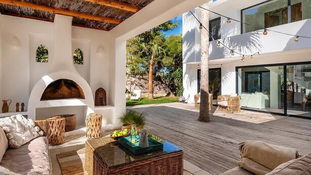 Un espacio exterior moderno con chimenea, zona de estar y vistas del paisaje circundante.