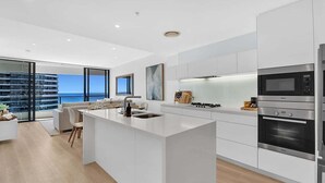 A modern kitchen with a central island, stainless steel appliances, and a view of the sea. - Ocean Getaway at Oracle Level 28 (Gold Coast)