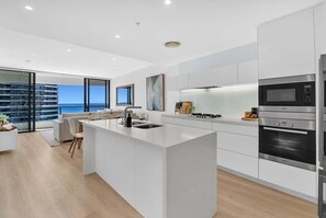 A modern kitchen with a central island, stainless steel appliances, and a view of the sea. - Ocean Getaway at Oracle Level 28 (Gold Coast)