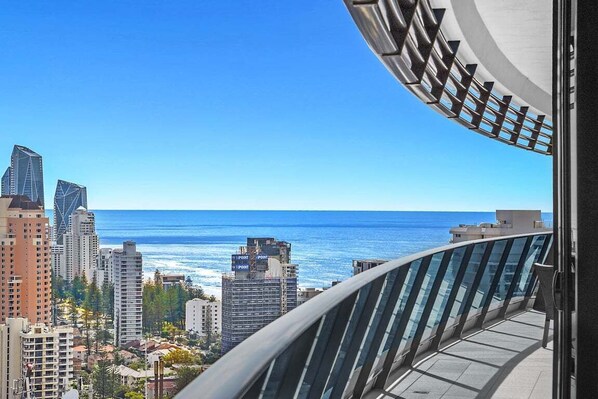 A high-rise building with a glass railing overlooking a cityscape and the ocean. - Beach Breeze Skyhome at Oracle Level 32 (Gold Coast)