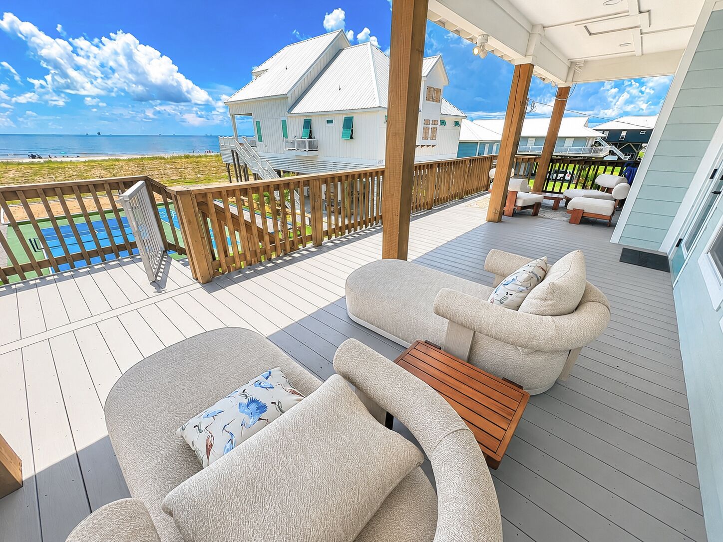 Eine überdachte Terrasse im Freien mit Pool, Liegestühlen und Blick auf den Strand.