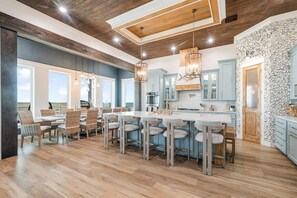 A spacious kitchen with a large island, wooden ceiling, and stone wall backsplash. - Bourbon Bay and Whiskey Lullaby Beachfront, Pool, Pickle Ball Court, Fire Pit and Much More (Grand Isle)