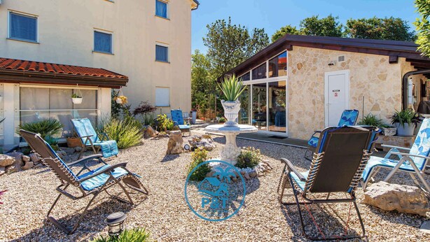 A building with a stone facade, outdoor seating area with lounge chairs, a small fountain, and potted plants. - Holiday flat with balcony and views of greenery (Klimno)