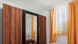 A bedroom with a bed, a wardrobe, and a window with curtains. - Holiday flat with balcony and views of greenery (Klimno)