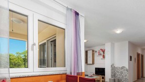 Una habitación con un ventanal grande, zona de comedor, televisor y pared de piedra.