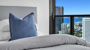 Un cuarto de hotel con cama, un ventanal grande y vistas de la ciudad.