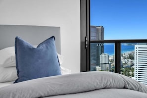 A hotel room with a bed, a large window, and a view of the cityscape. - Ocean Sunset Skyhome at Oracle Level 33 (Gold Coast)