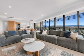 A modern living room with two grey sofas, a coffee table, and a view of the city. - Ocean Sunset Skyhome at Oracle Level 33 (Gold Coast)