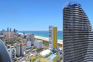 A high-rise hotel with a curved facade, a pool, and a view of the beach and ocean. - Beach Skyhome at Oracle Level 37 (Gold Coast)