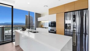 Uma cozinha moderna com uma ilha grande, eletrodomésticos de aço inoxidável e vista para a paisagem urbana.