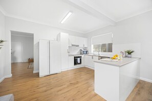 A modern kitchen with white cabinetry, a built-in oven, a microwave, and a large window.