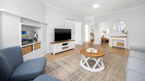 Ein modernes Wohnzimmer mit Flachbildfernseher, rundem Couchtisch und Sofa.