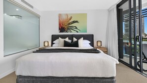 A hotel room with a bed, a large window, a painting, and a view of buildings. - Beach Getaway at Oracle Level 6 (Gold Coast)