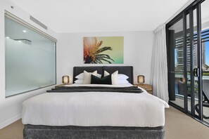 Ein Hotelzimmer mit einem Bett, einem großen Fenster, einem Gemälde und Blick auf Gebäude.