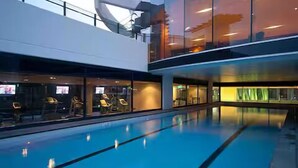 An indoor swimming pool with a modern design, glass walls, and a view of the cityscape. - Beach Getaway at Oracle Level 6 (Gold Coast)