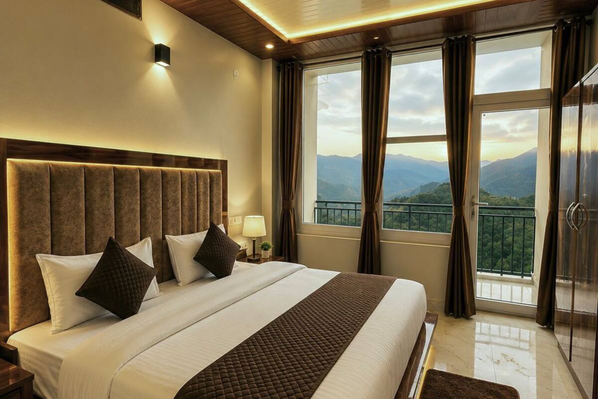 Un dormitorio amplio con una cama grande, un ventilador de techo, una mesita de noche y vistas a las montañas a través de la ventana.