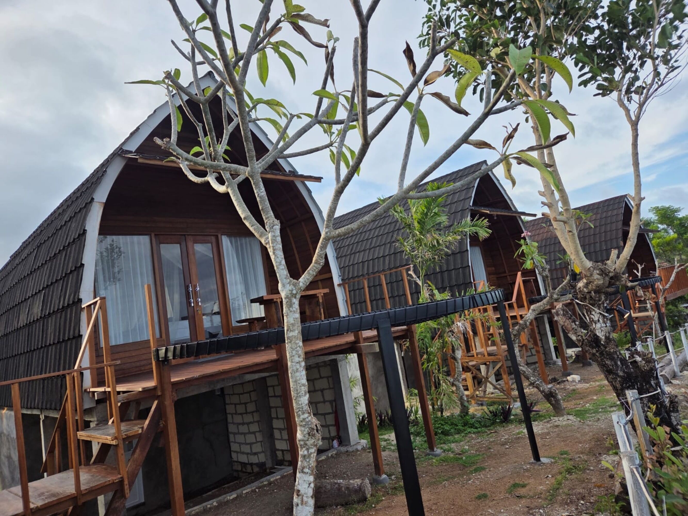 A row of wooden cabins with a covered deck area and a brick foundation.