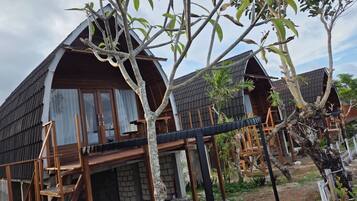 A row of wooden cabins with a covered deck area and a brick foundation.