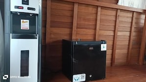 Ein kompakter, schwarzer Kühlschrank, ein graues Sofa und eine Holzvertäfelung.
