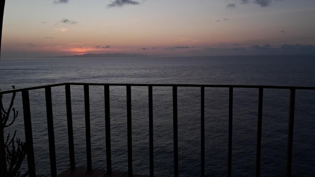 A balcony with a view of the sea during sunset.
