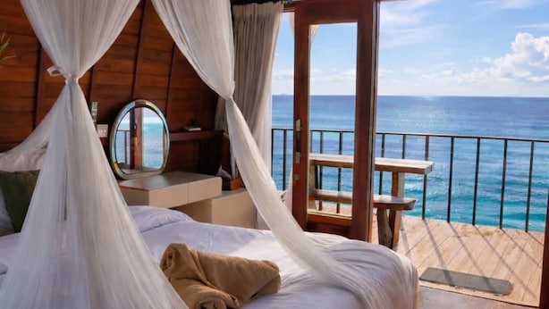 Ein Schlafzimmer mit Bett, Nachttisch, Spiegel und Meerblick.