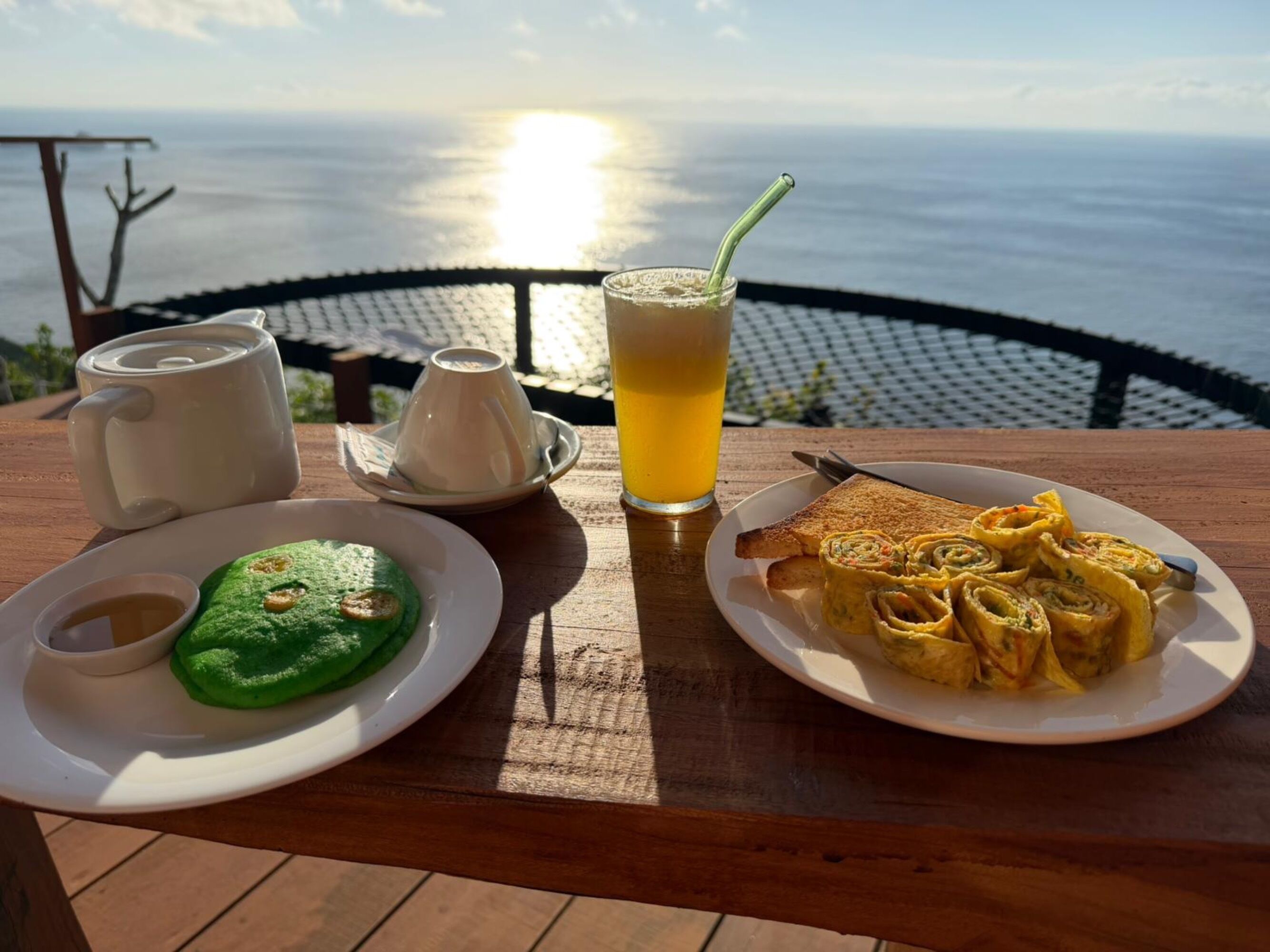 Une table avec une assiette de nourriture, un verre de jus de fruits et une théière.