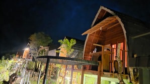 Eine Holzhütte mit Balkon, umgeben von viel Grün.