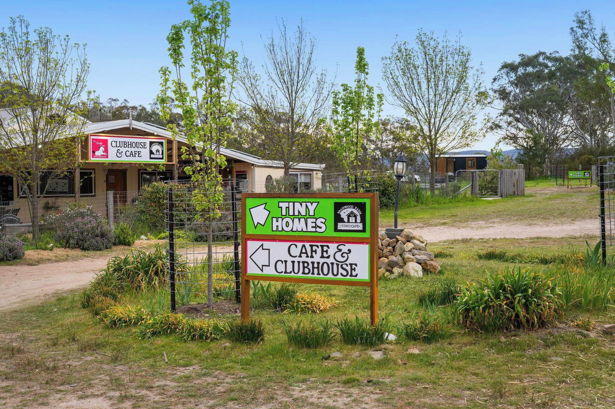 A sign for Tiny Homes with directions to a cafe and clubhouse.