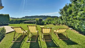 A garden with four striped lawn chairs and a table. - Sea View Golf Retreat. Los Arqueros Benahavís (Benahavís)