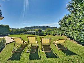 A garden with four striped lawn chairs and a table. - Sea View Golf Retreat. Los Arqueros Benahavís (Benahavís)