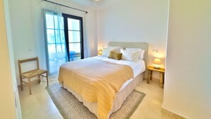 A bedroom with a bed, a chair, a nightstand, a ceiling fan, and a window with curtains. - Sea View Golf Retreat. Los Arqueros Benahavís (Benahavís)