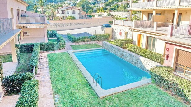 Uma área residencial com piscina, cercada por gramados e sebes bem cuidados.