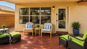 A covered patio with wicker furniture, a door, and a window. - Norterra Desert Escape: Heated Pool, Walk to Pickleball – Sleeps 5  (Phoenix)