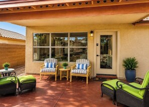 A covered patio with wicker furniture, a door, and a window. - Norterra Desert Escape: Heated Pool, Walk to Pickleball – Sleeps 5  (Phoenix)