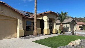 A residential house with a garage, a well-maintained lawn, and a palm tree. - Norterra Desert Escape: Heated Pool, Walk to Pickleball – Sleeps 5  (Phoenix)