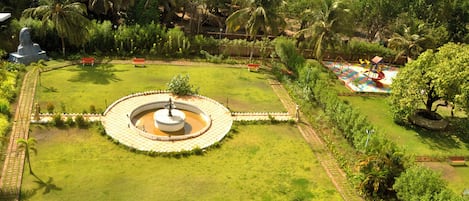 Un parque con una fuente circular, bancos y un área de juegos.