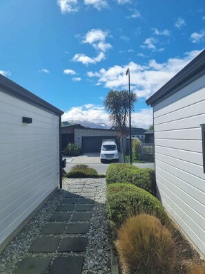 Un étroit sentier mène à un bâtiment blanc devant lequel est garée une voiture.