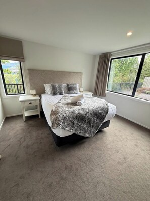 Une chambre à coucher avec un grand lit, une table de chevet, une fenêtre donnant sur un beau paysage et un luminaire au plafond.