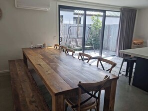 Ein Essbereich mit einem langen Holztisch, Stühlen und einer Küchenarbeitsplatte.