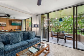 Ein Wohnzimmer mit Sofa, Couchtisch und einem Balkon mit Gartenmöbeln.