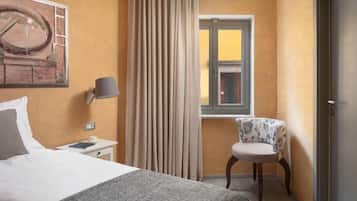 Ein Hotelzimmer mit Bett, Stuhl, Lampe, Fenster und Tür.
