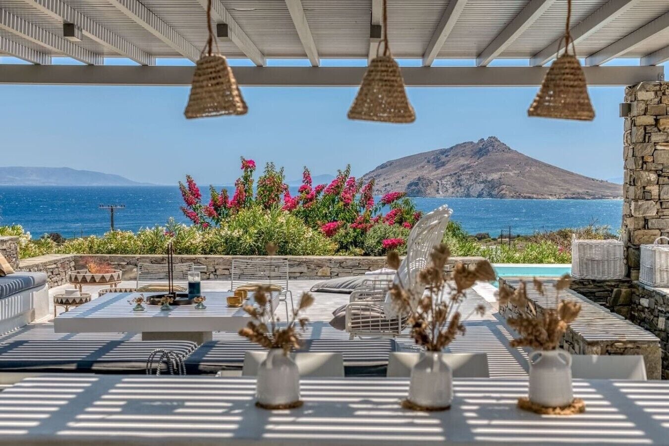 An outdoor seating area with a view of the sea and a mountain.