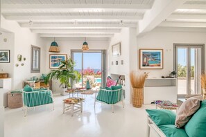 A spacious living area with a view of the sea, a balcony, and a dining area with a table and chairs. - Villa La Magnifique - The best view (Naousa)