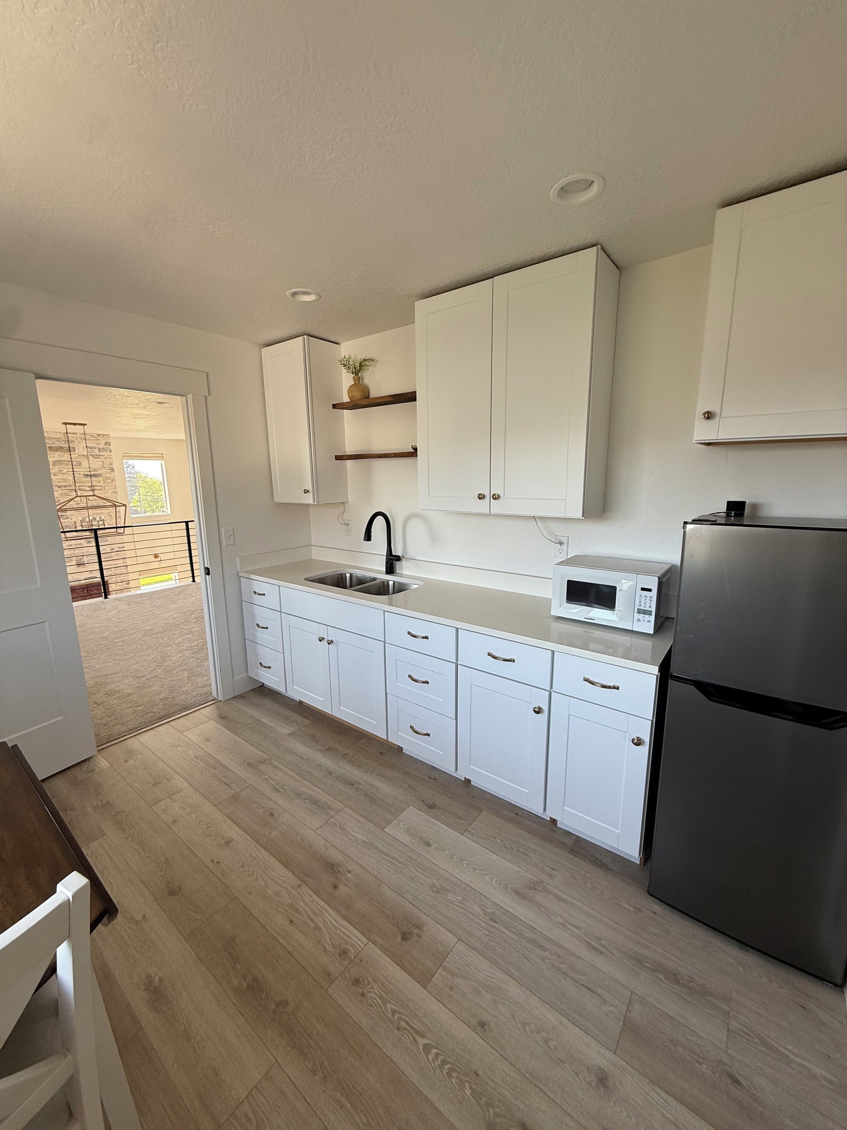 A modern kitchen with white cabinetry, a stainless steel refrigerator, and a built-in microwave.