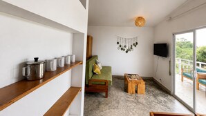 A modern living room with a sofa, coffee table, and shelves with kitchen items. - Samsara - Villa Cappucino (Koh Rong)